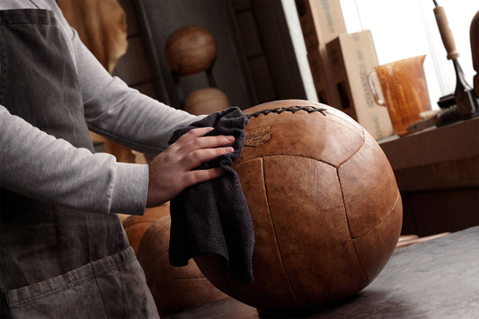 Mann wischt mit einem Lappen über einen ARTZT Vintage Series Medizinball.